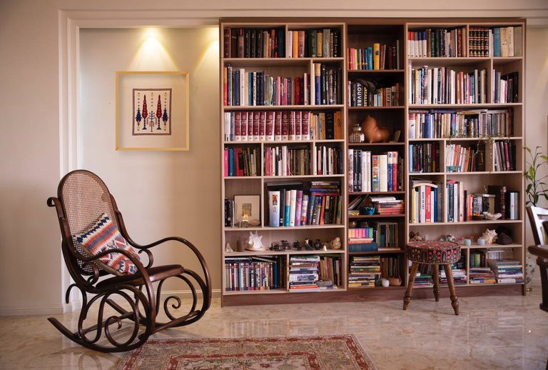 A framed motif in a room with bookshelves and a rocking chair