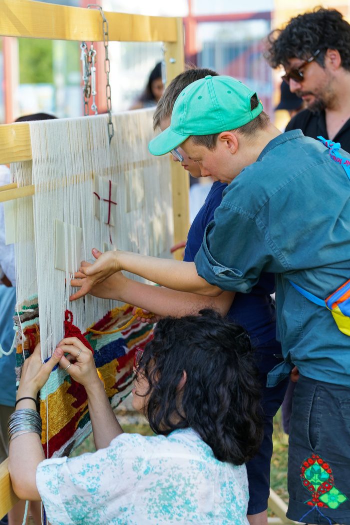 Participants weaving together at an upright loom