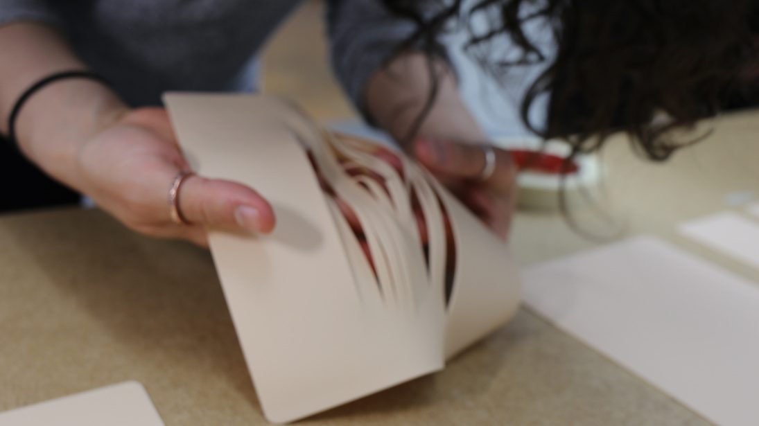 Hands opening a cut paper surface