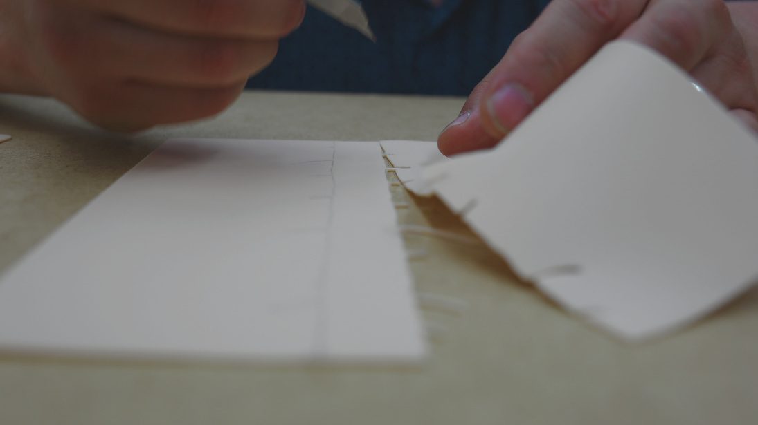 Hands folding white paper