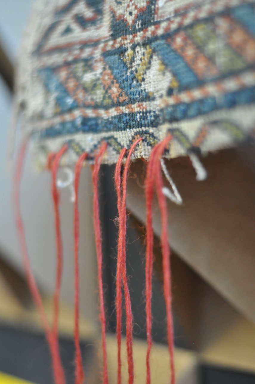 A carpet fragment with loose red threads
