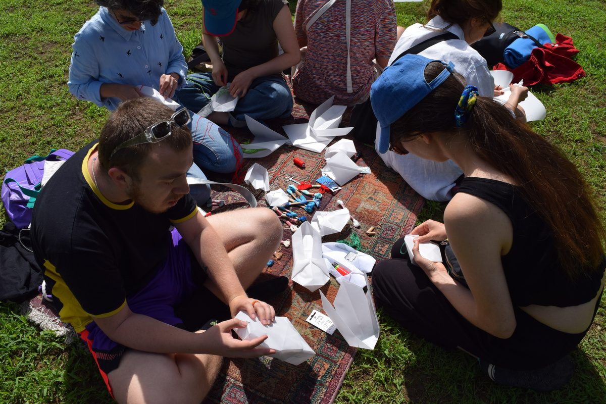 Participants sewing paper squares in the park