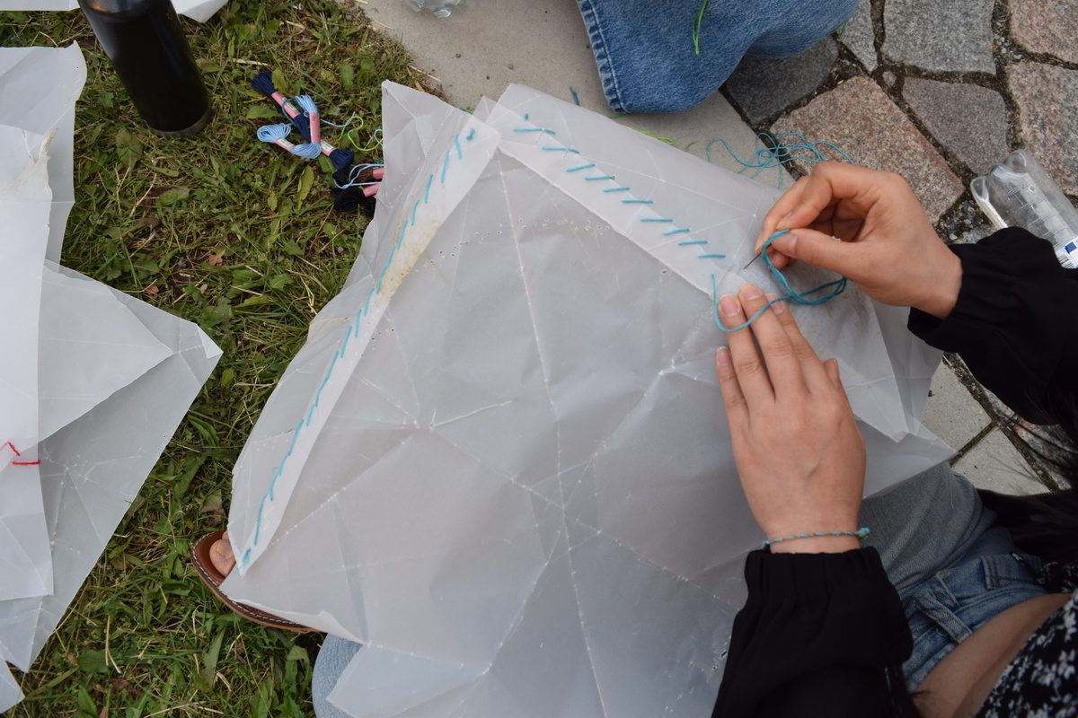 Hands stitching paper together