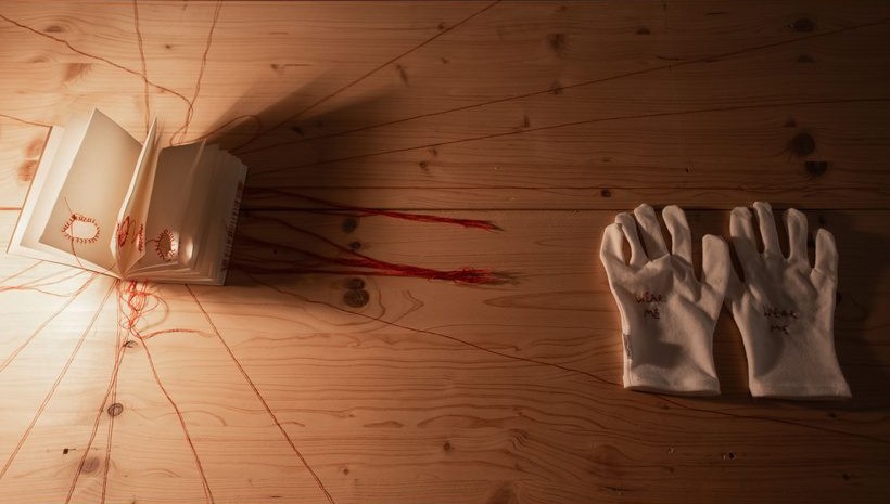 White gloves and threads on a wooden table